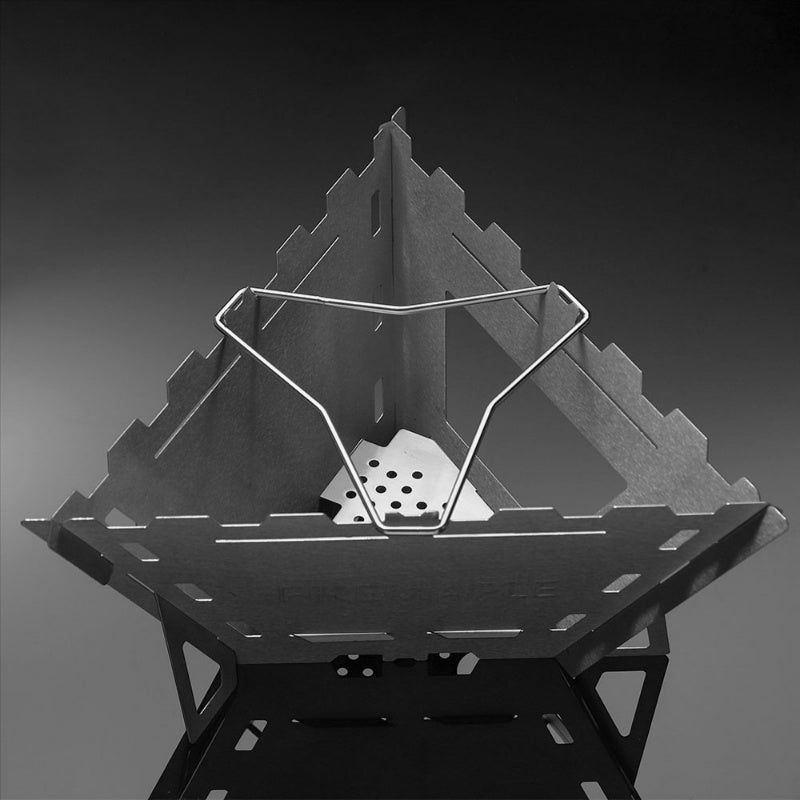 A stainless steel triangle-shaped wood stove with a foldable grill, displayed in black and white.