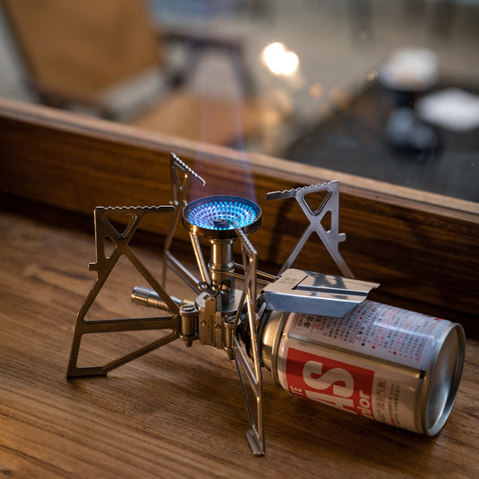 Campingmoon XD‑3 butane stove in action—blue flame burning from foldable burner in cozy indoor setting