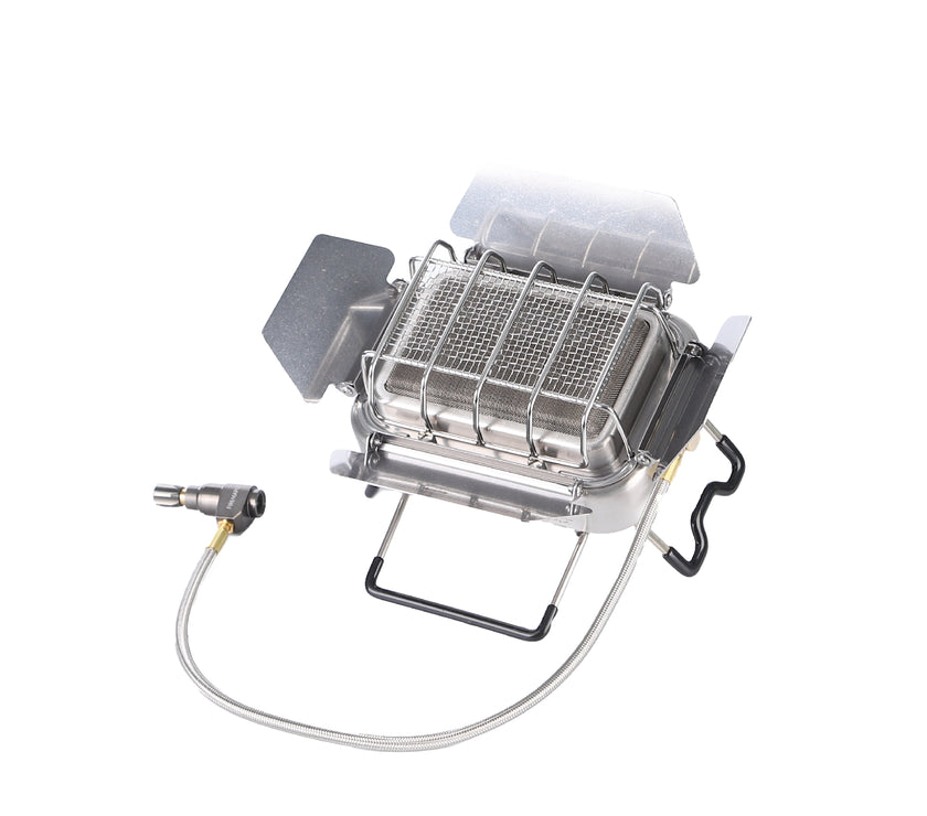 A silver portable camping stove with a foldable design and a gas connection hose.