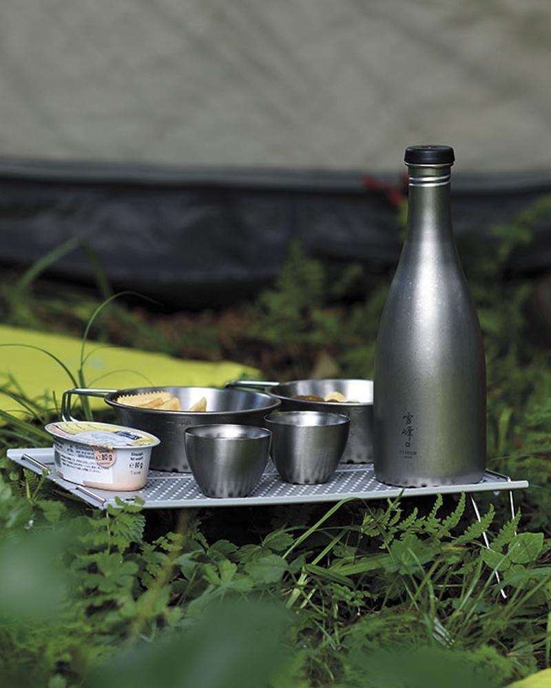 Snow Peak Ozen Solo Table SLV-171 set up outside a tent, holding titanium sake bottle, cups and bowls (not included)