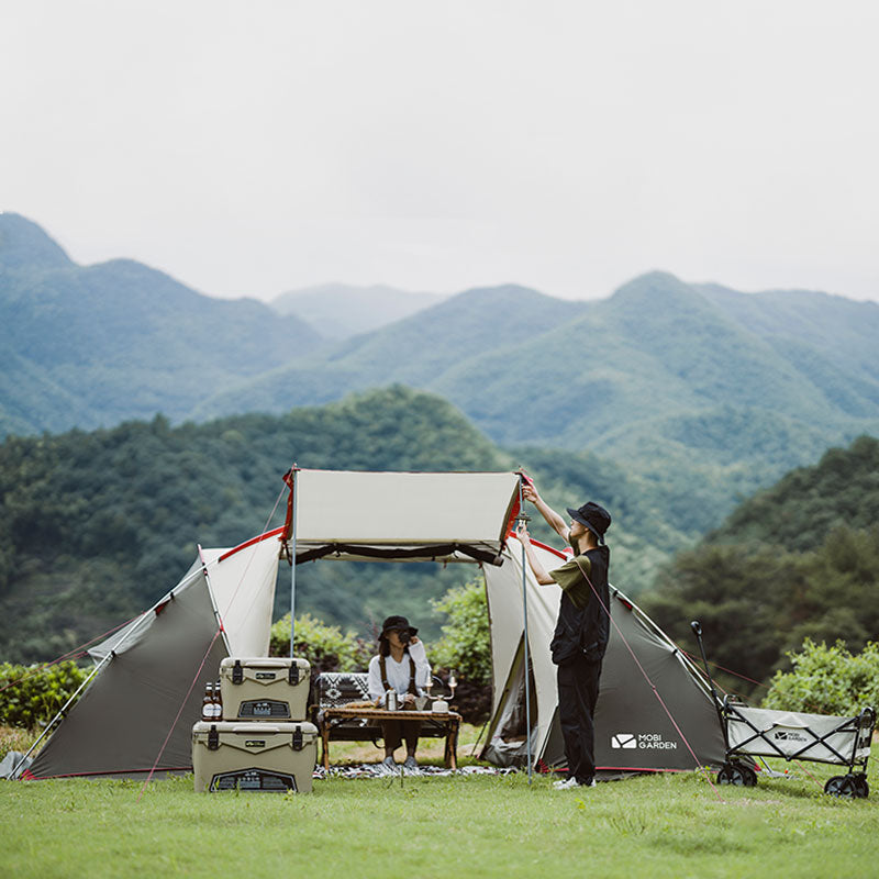 Two people setting up a tent in a scenic outdoor setting with mountains in the background.
