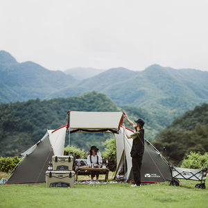 Two people setting up a tent in a scenic outdoor setting with mountains in the background.