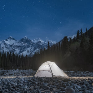 Tent illuminated in a snowy mountain landscape under a starry night sky.