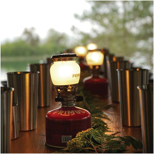 Primus EasyLight lantern casting warm glow at dusk in outdoor camping setting