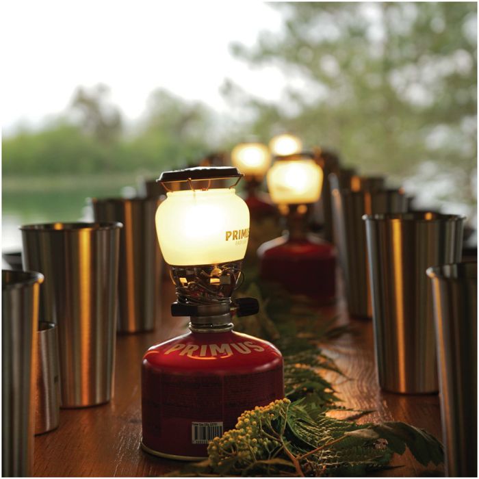 Primus EasyLight lantern casting warm glow at dusk in outdoor camping setting