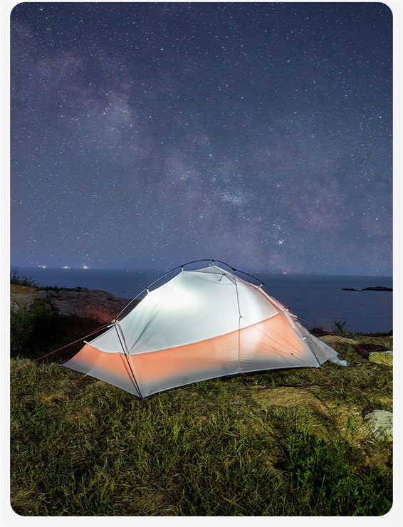 Camping tent under a starry night sky with ocean view