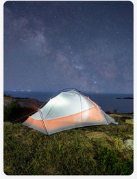 Camping tent under a starry night sky with ocean view