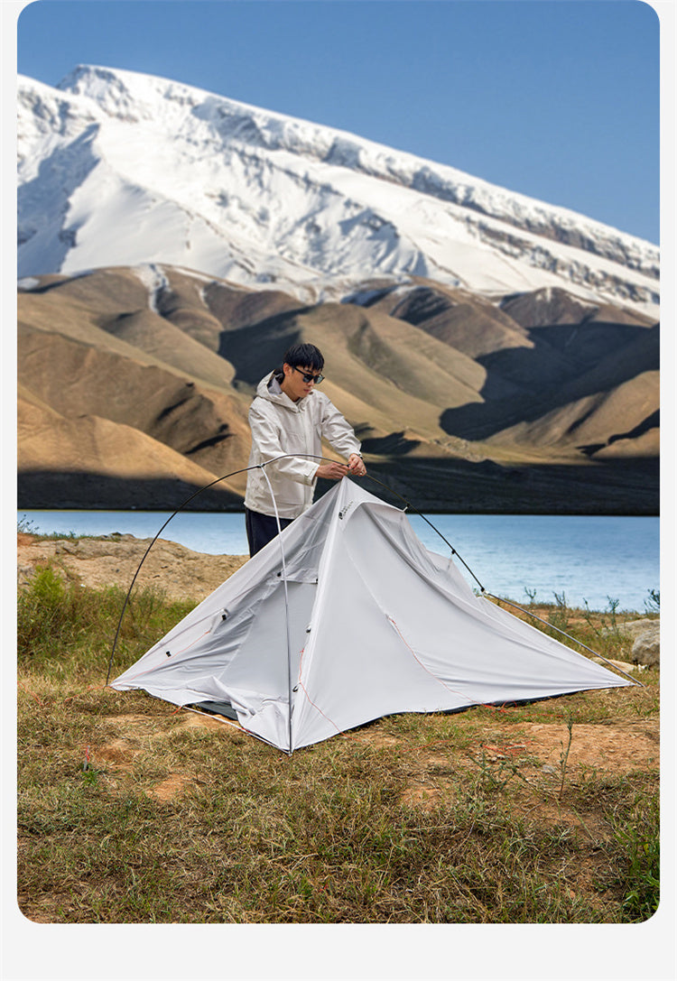 Person setting up a tent in a mountainous landscape
