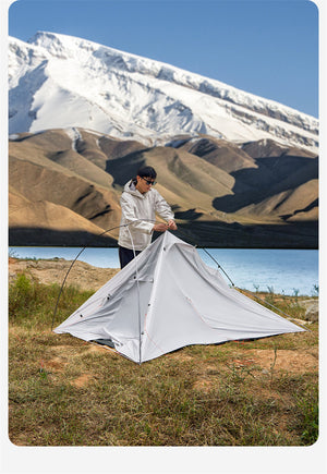 Person setting up a tent in a mountainous landscape