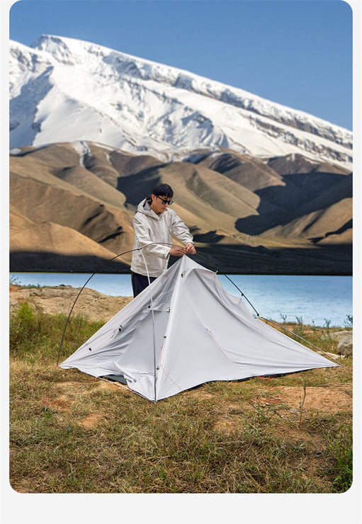 Person setting up a tent in a mountainous landscape