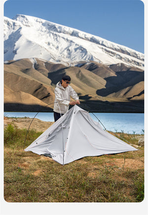 Person setting up a tent in a mountainous landscape