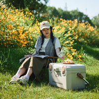 A girl sitting next to Naturehike Ling Xia cooler with drink on hand