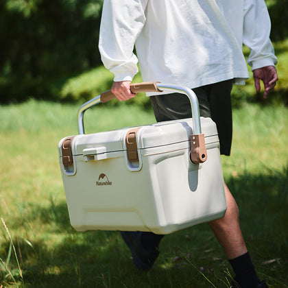 A guy holding the Naturehike Ling xia Cooler walking on the grass