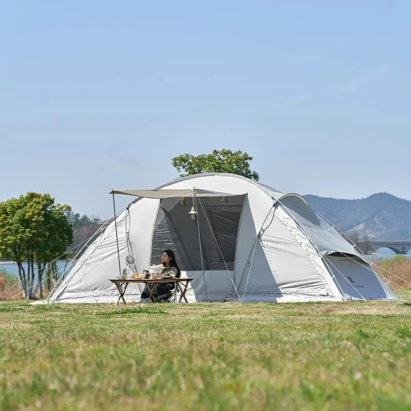 Person sitting at a table outside a large tent in a scenic outdoor setting