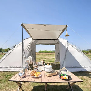 Camping scene with a tent, table, and outdoor setup under a clear blue sky.