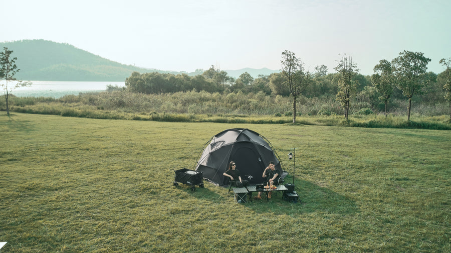 Tent set up in a grassy field with a scenic background