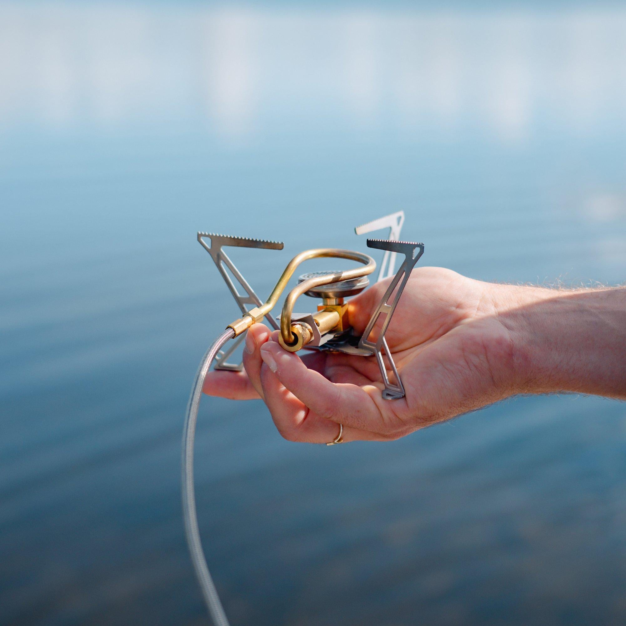 Hand holding the folded Primus Express Spider Stove to show its lightweight compactness