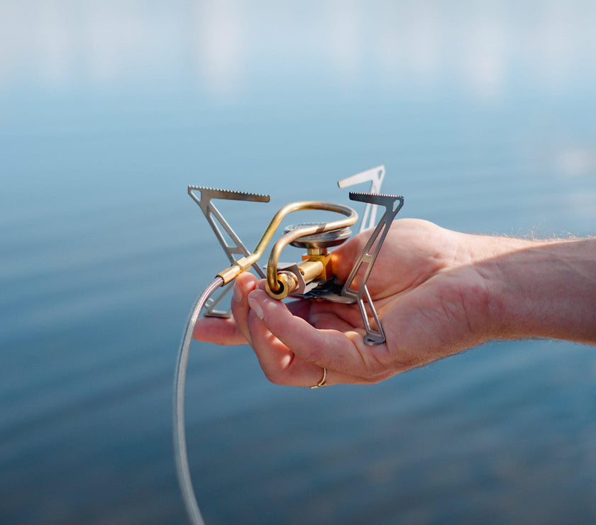 Hand holding the folded Primus Express Spider Stove to show its lightweight compactness