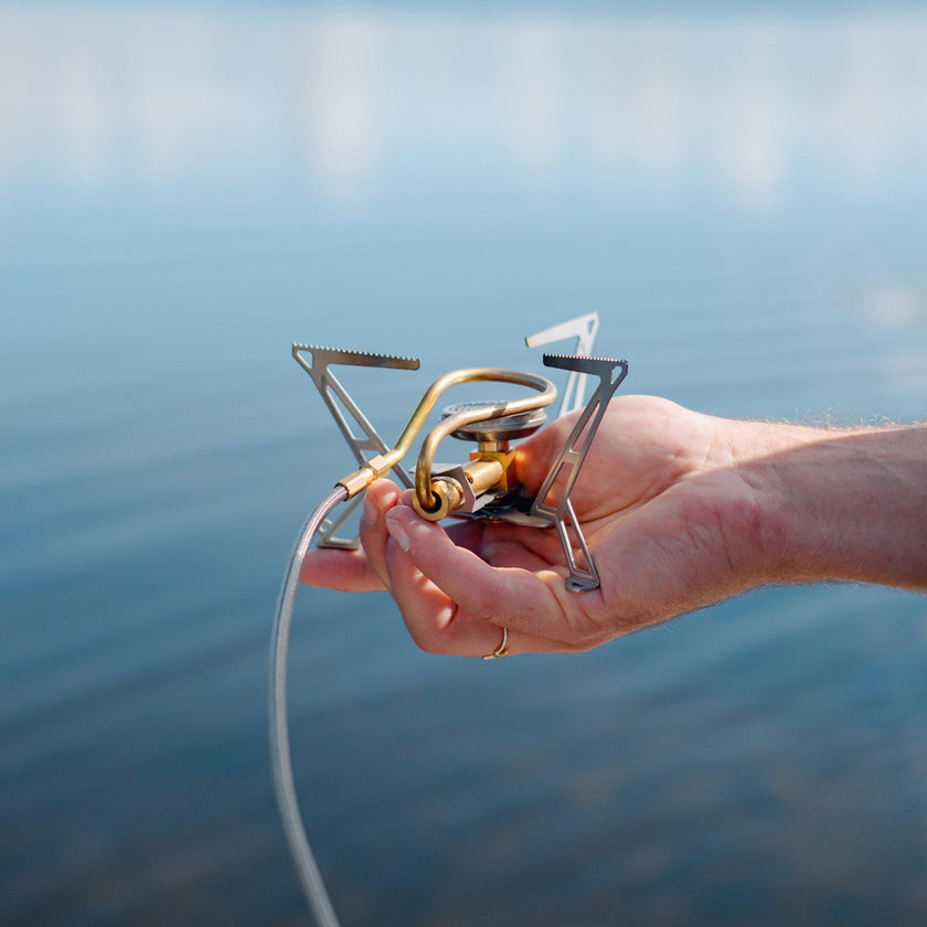 Hand holding the folded Primus Express Spider Stove to show its lightweight compactness