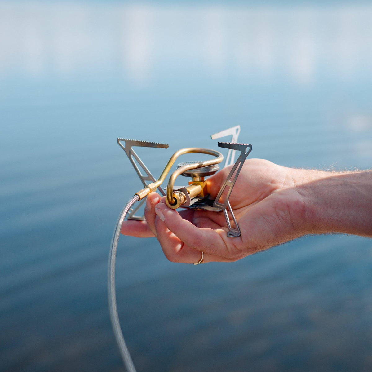 Hand holding the folded Primus Express Spider Stove to show its lightweight compactness