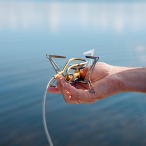 Hand holding the folded Primus Express Spider Stove to show its lightweight compactness