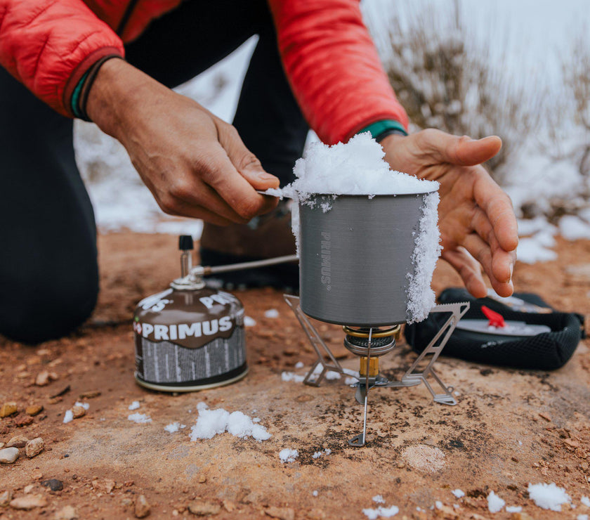Primus Express Spider components laid out: stove, reflector plate, and carry bag on ground
