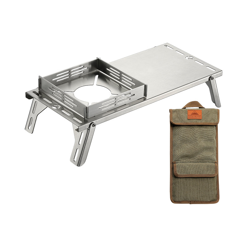 A silver stainless steel camping table with integrated windbreak and heat insulation, displayed alongside a carrying bag.
