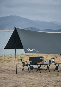Outdoor setup with a black Mobi Garden tarp and furniture against a mountainous background.