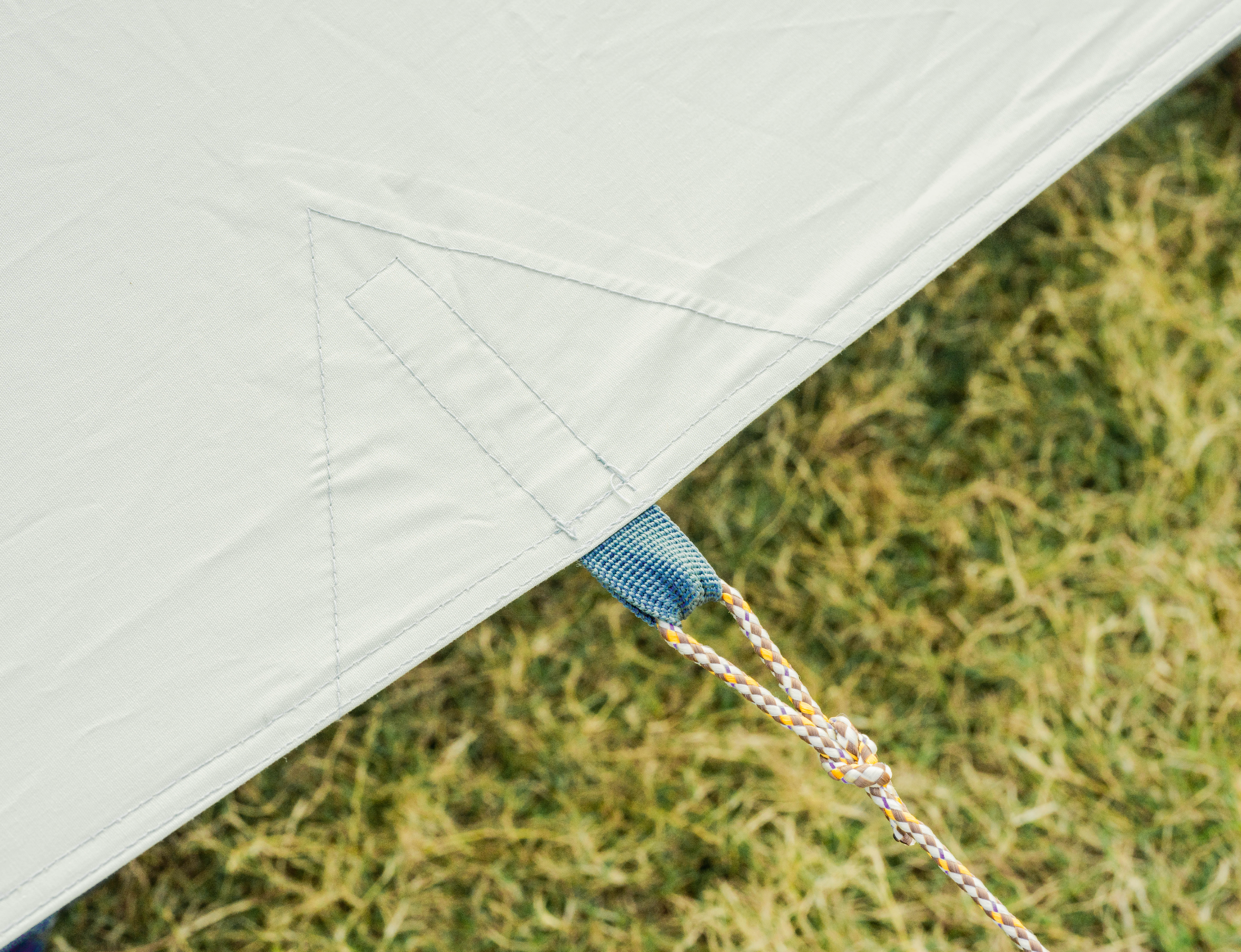 Close-up of a tent's corner with grass in the background