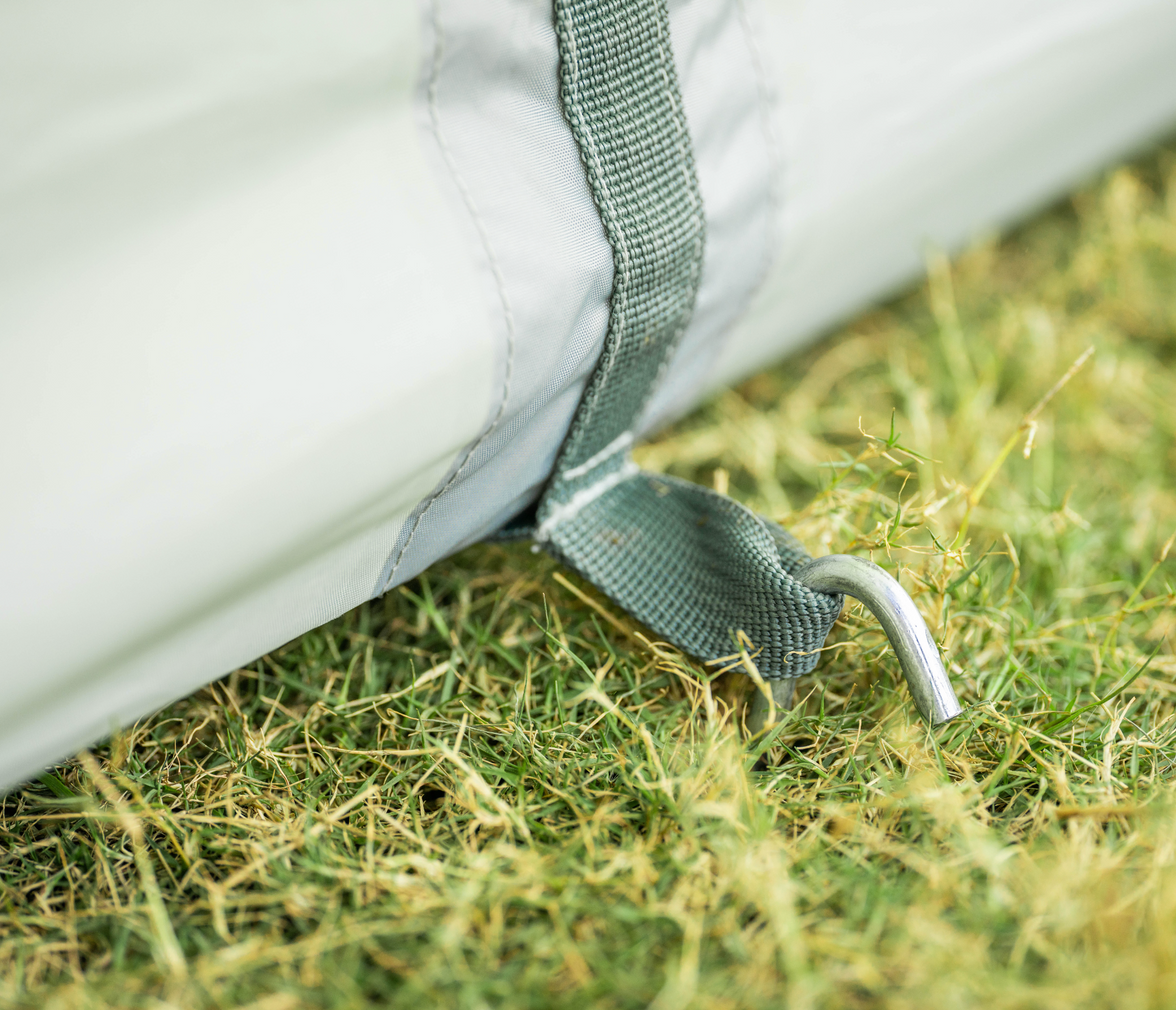 Close-up of a white tent with green straps on grass