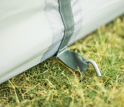 Close-up of a white tent with green straps on grass