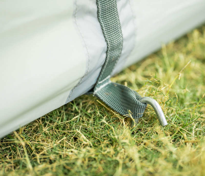 Close-up of a white tent with green straps on grass