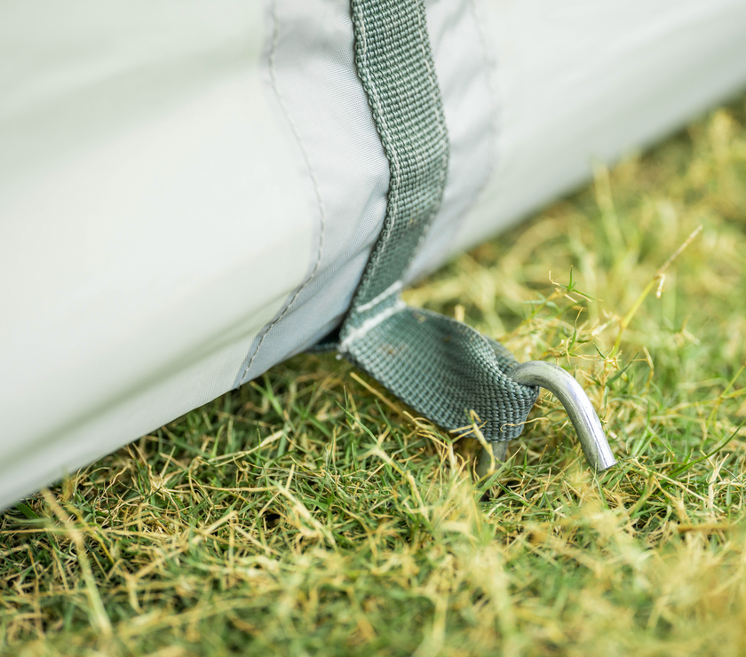 Close-up of a white tent with green straps on grass
