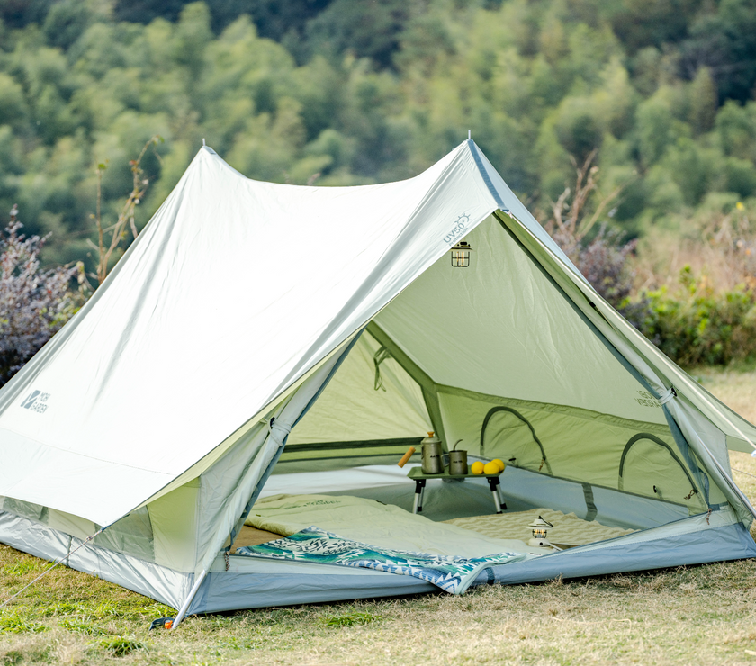 Camping tent set up in a grassy area with trees in the background
