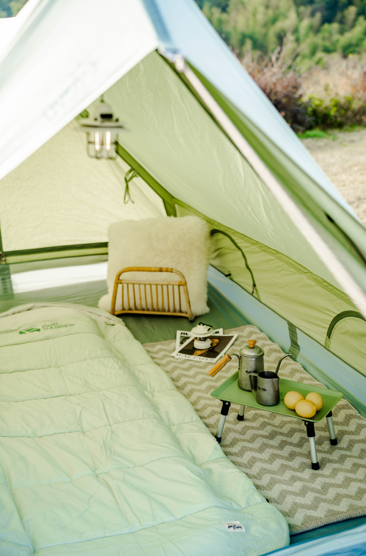 Camping setup inside a tent with a small table, pillows, and camping gear.
