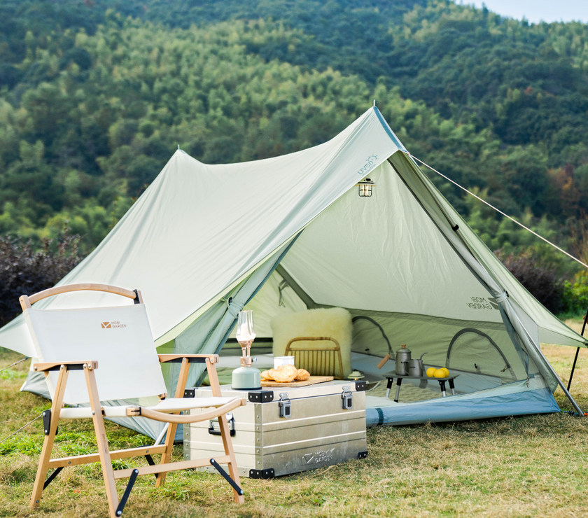 Bell tent in a natural setting with outdoor furniture and supplies.