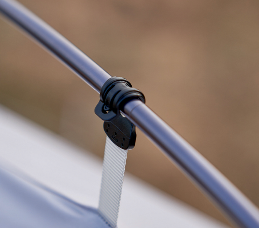 Close-up of a metal rod with a black strap and white rope against a blurred background