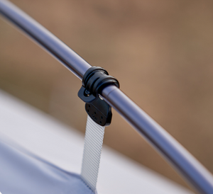 Close-up of a metal rod with a black strap and white rope against a blurred background