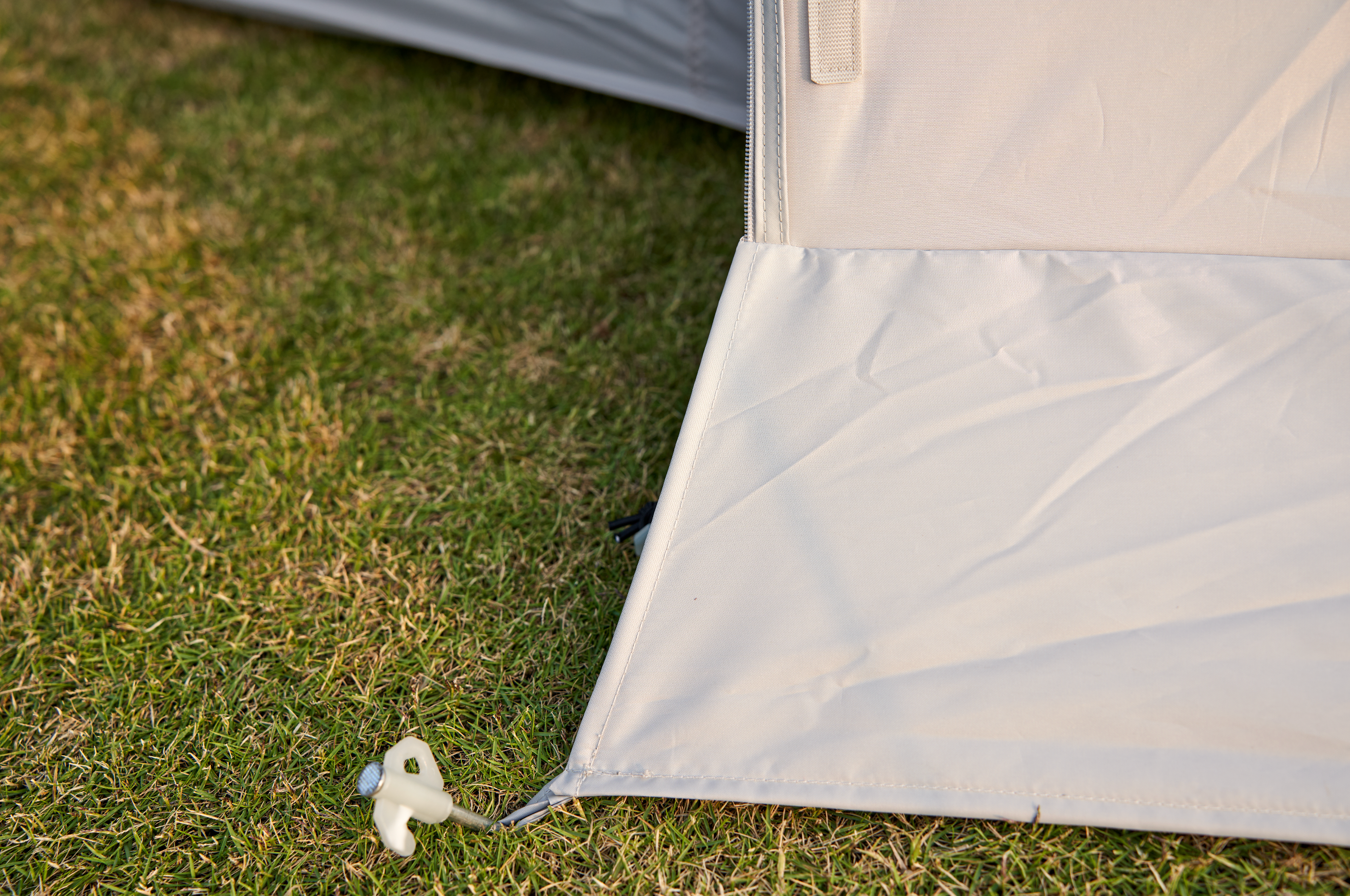 Close-up of a tent corner with grass in the background