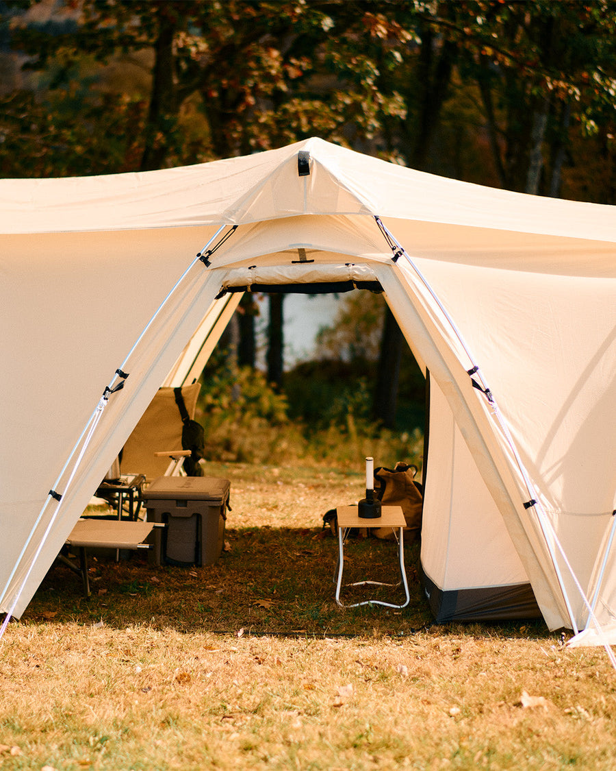 Snow Peak Land Nest Shelter TP-259 ivory canopy over a camp table, lantern and cooler in autumn woods