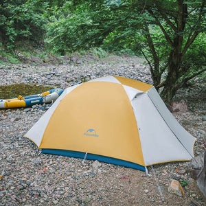 A yellow and gray Naturehike tent set up outdoors with trees in the background.