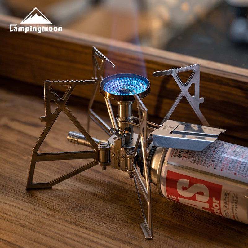 Campingmoon XD‑3 butane stove in action—blue flame burning from foldable burner in cozy indoor setting