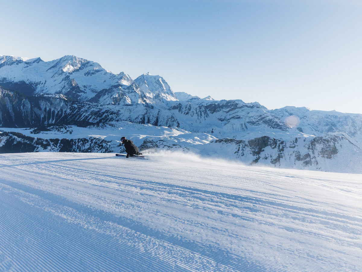 Skier carving under an Alpine ridge