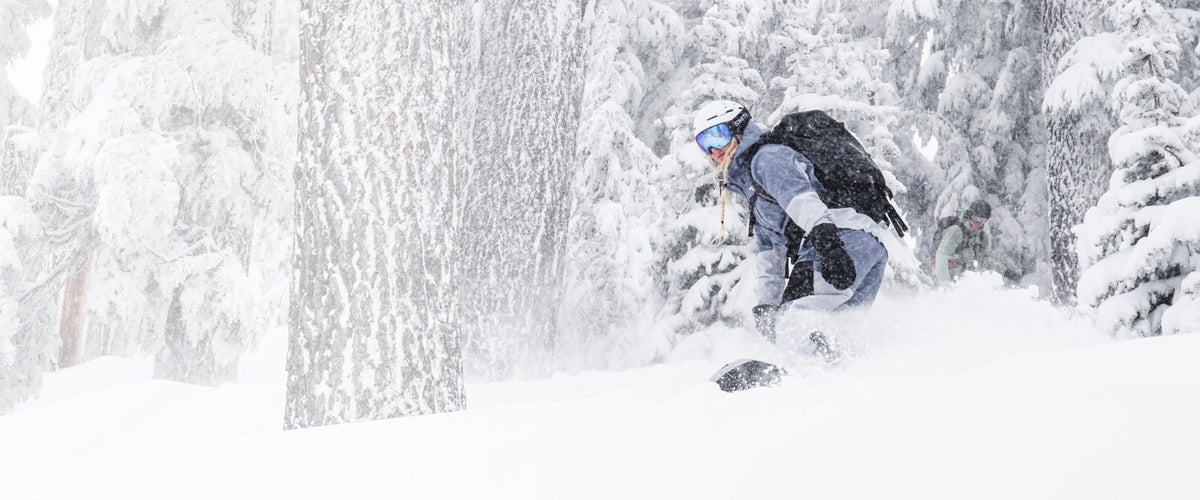 Snowboarder in deep powder among snow-loaded trees, wearing a Smith helmet and goggle