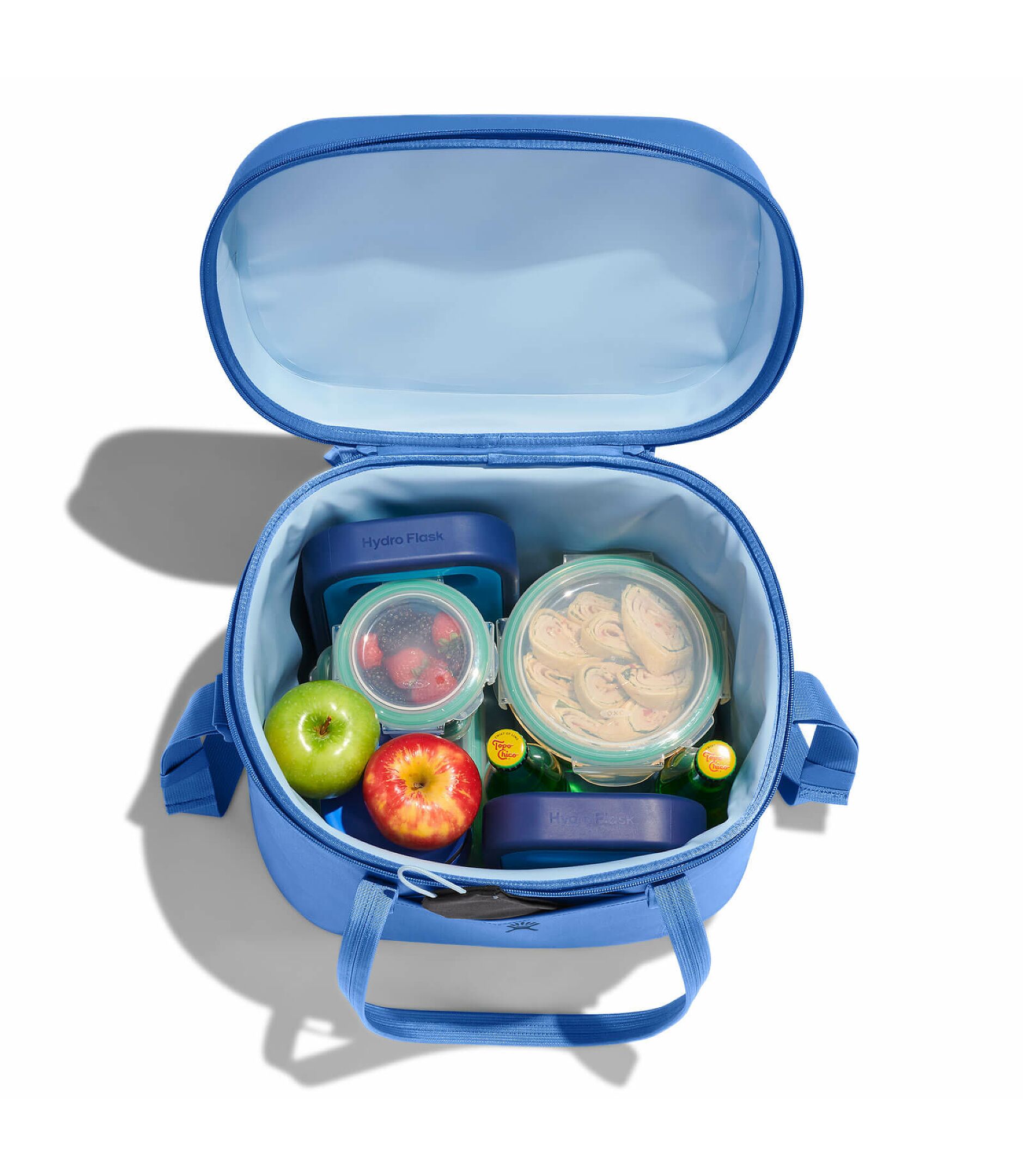 Blue lunch bag with food containers and apples on a white background