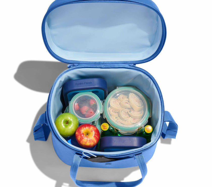 Blue lunch bag with food containers and apples on a white background