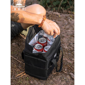 Person opening a black cooler bag filled with drinks on a natural ground surface.