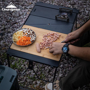 Campingmoon portable stove with a cutting board and food preparation on a rocky ground